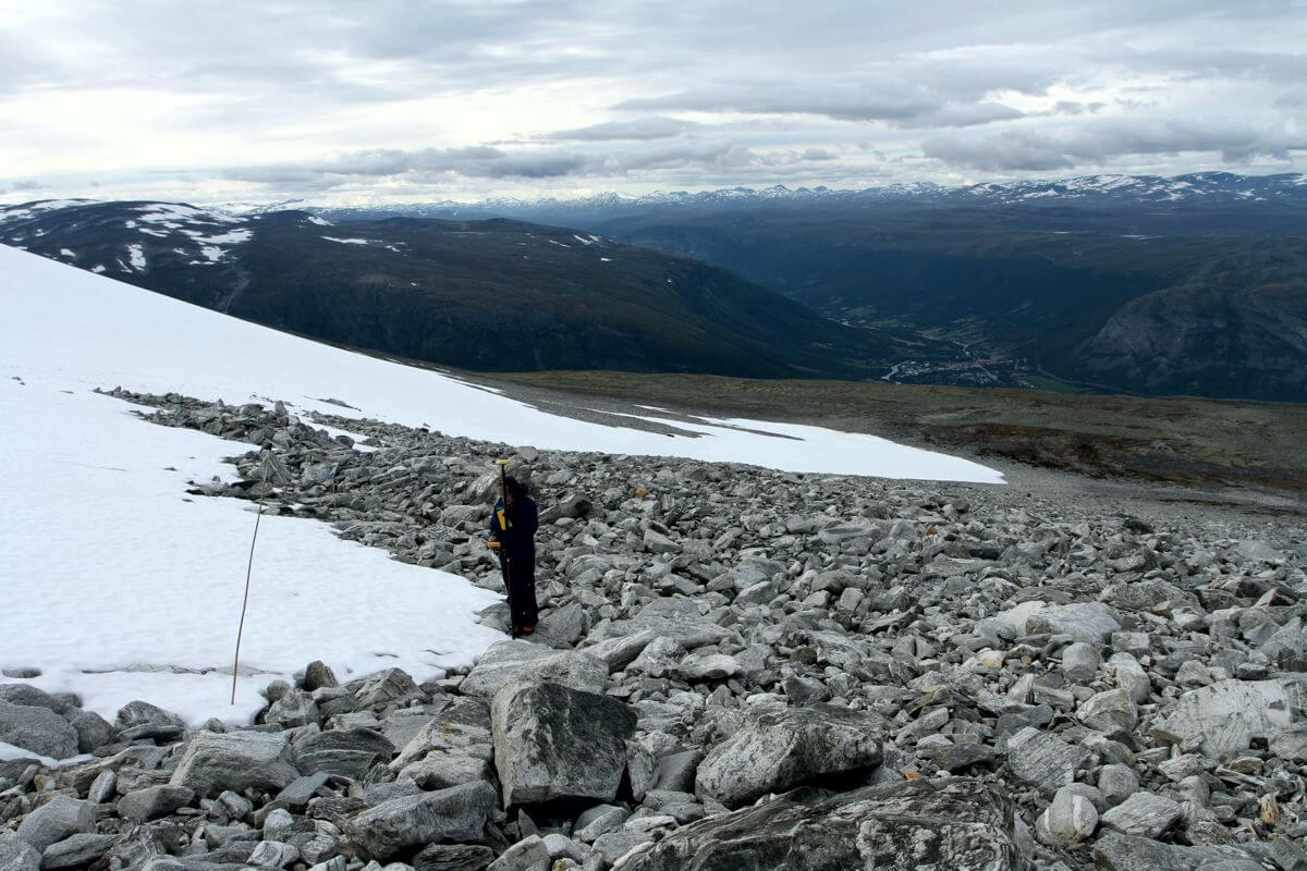 A glacial archaeologist measures the snow line at Åndfonne ice patch during the 2015 fieldwork.